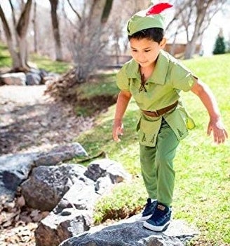 Child playing in Peter Pan costume near a rock