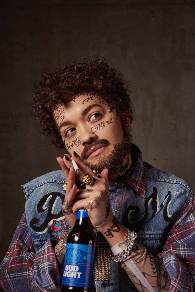 A heavily fake tattoed Rita holding a bottle of Bud light and a cigarette