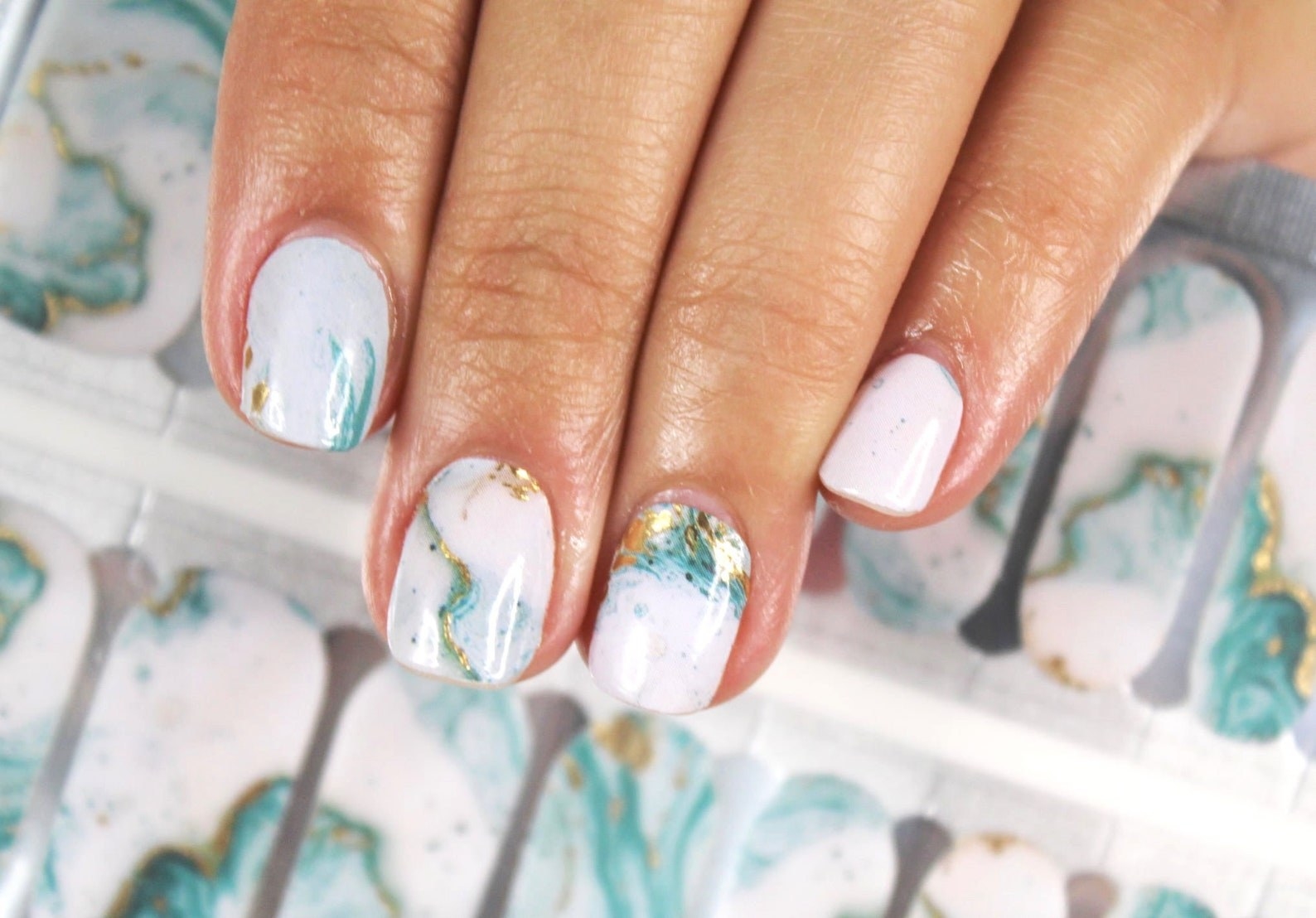 model with teal and white watercolor nail wraps on