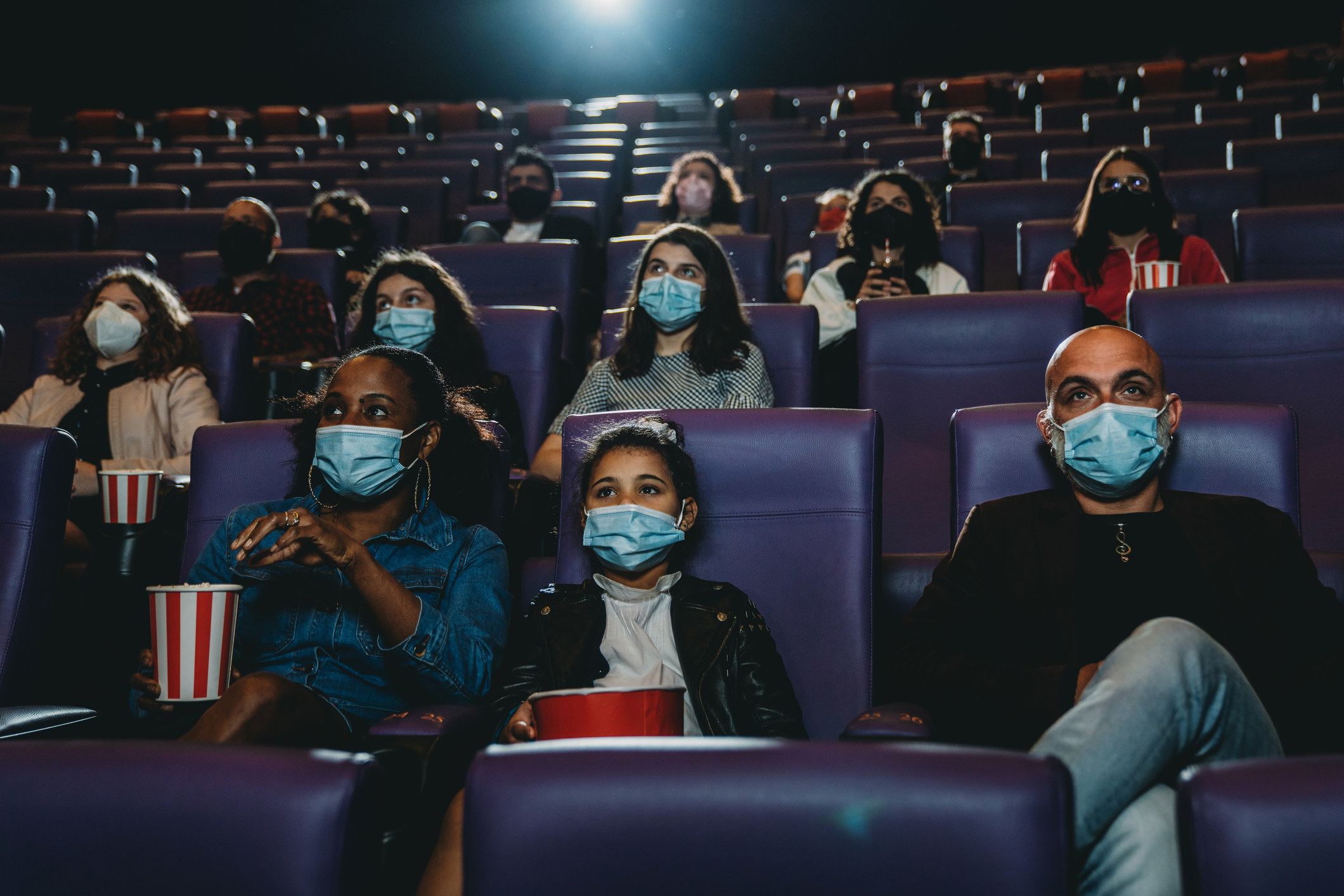 families social distancing in the cinema with masks on