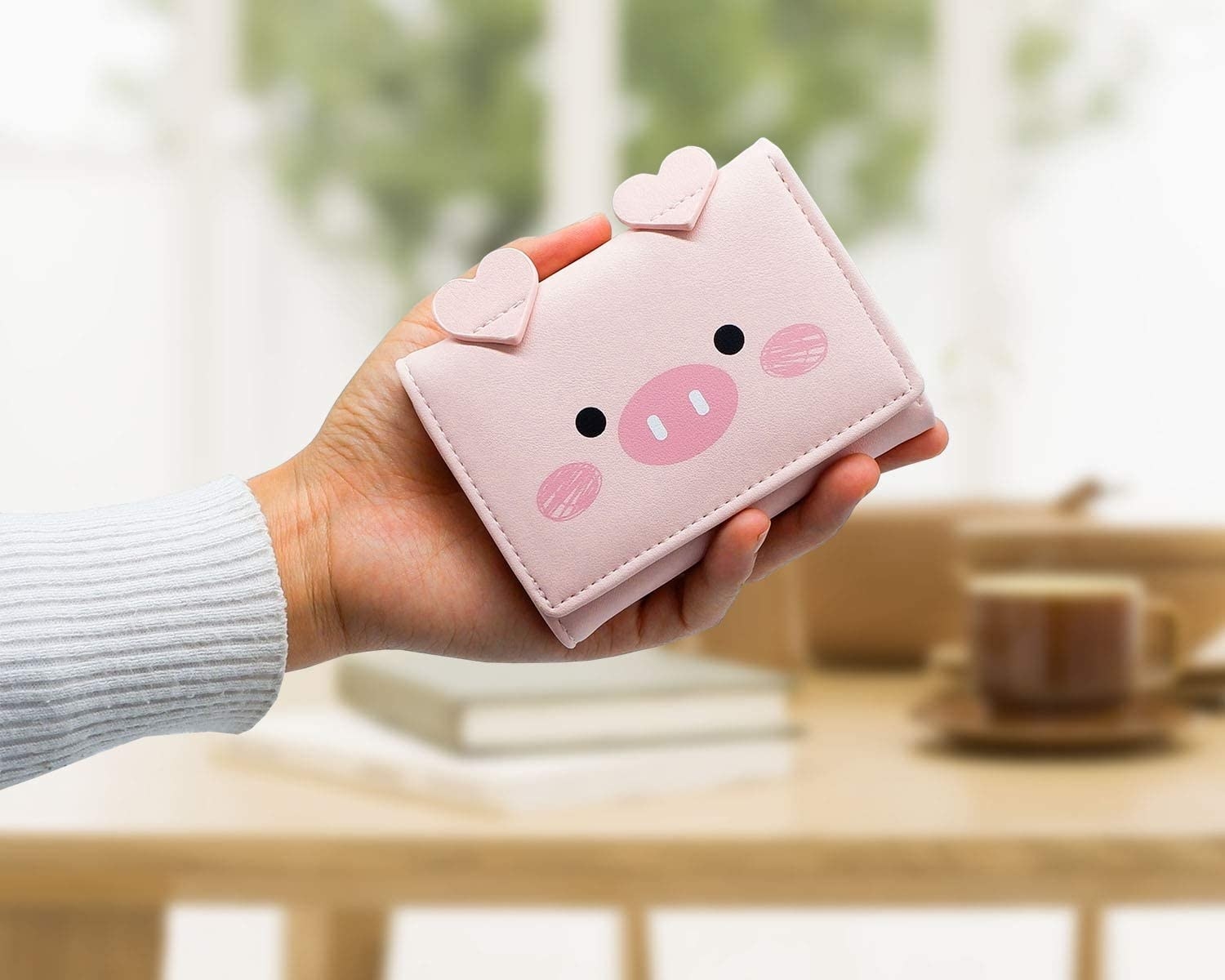 a person holding out a cute piglet-shaped wallet