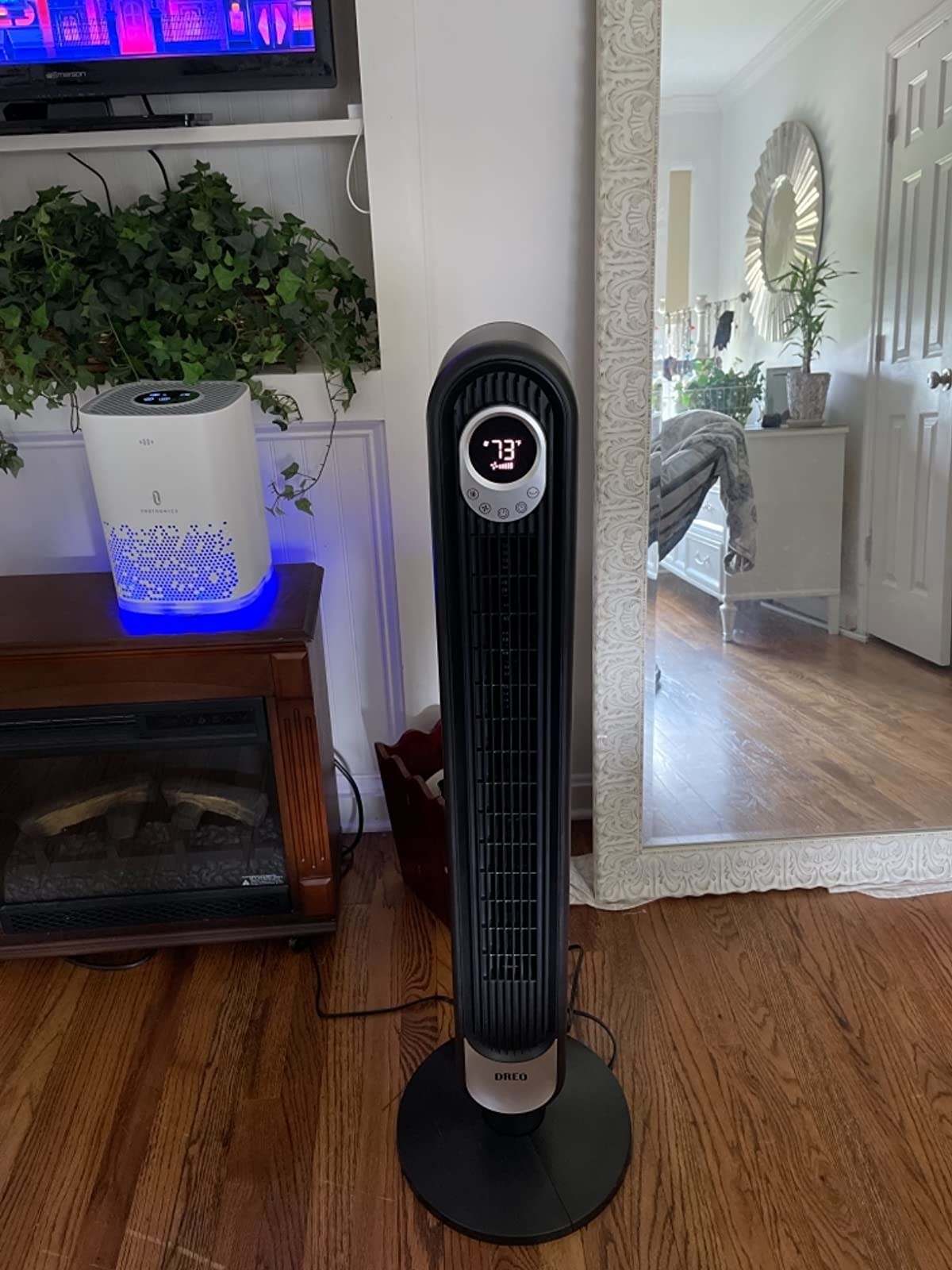 A reviewer's narrow black fan with a temperature reading of 73 on the led screen