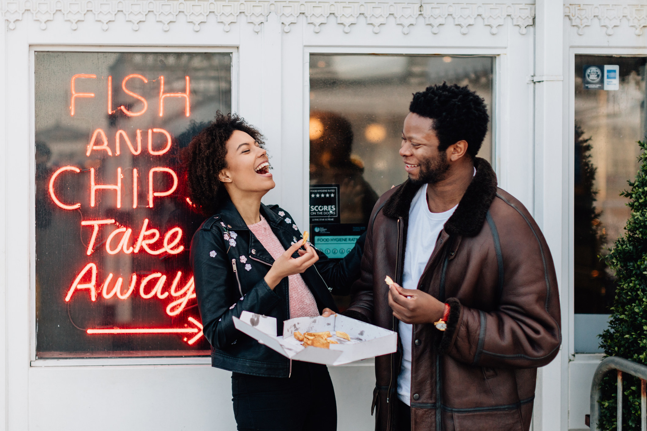 a couple eating takeaway outside of restaurant