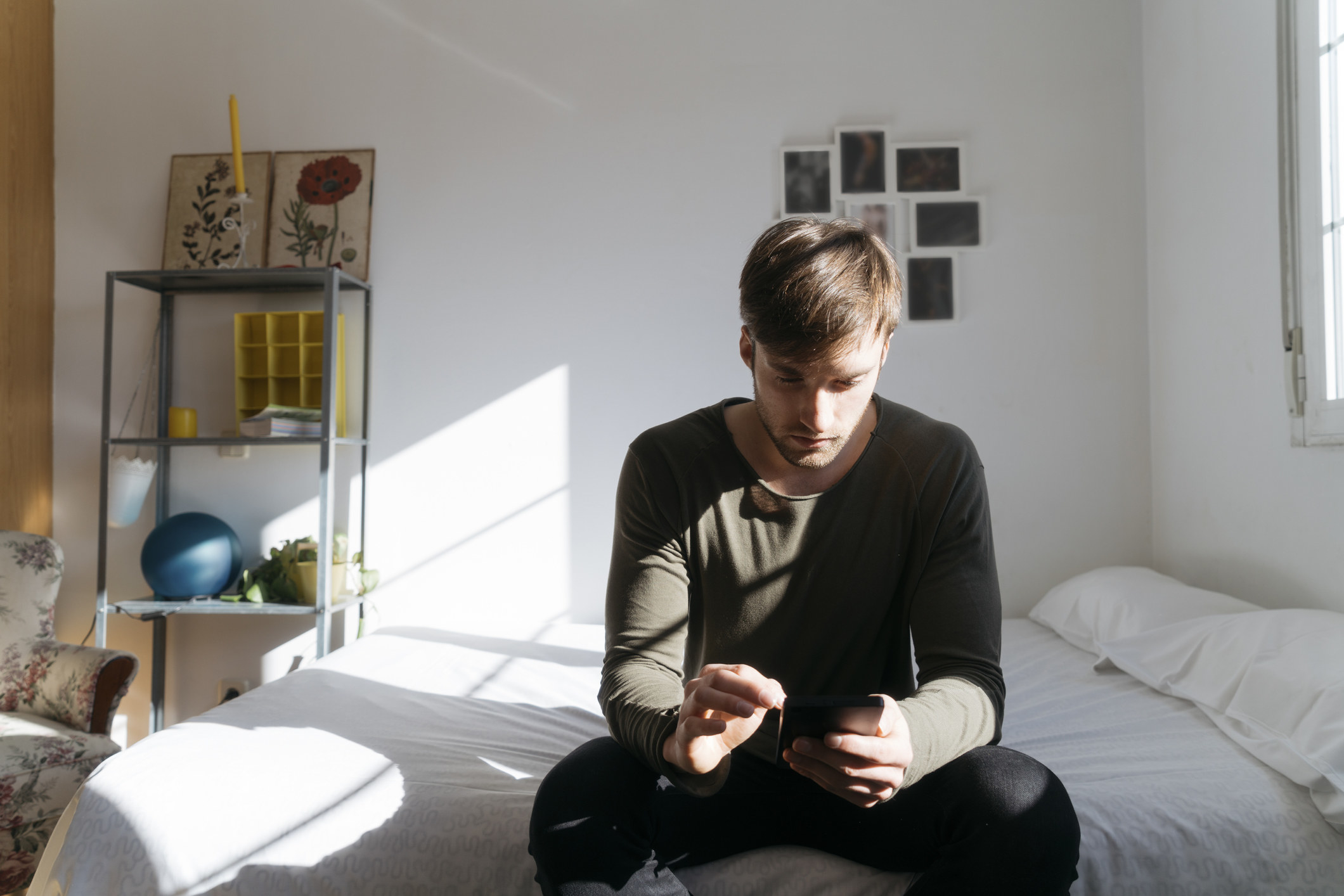 A guy sits alone on his phone, looking sad