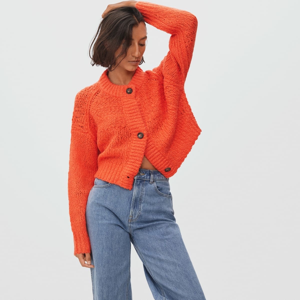 a model wearing the bright orange sweater with chunky buttons