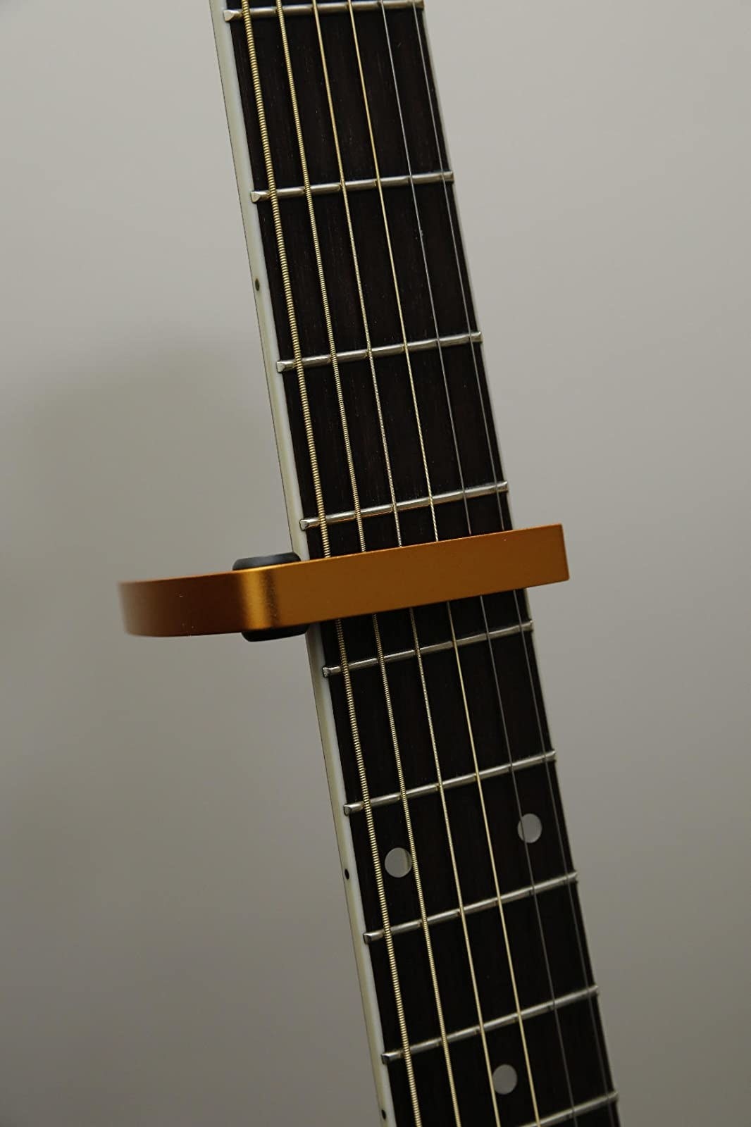 Reviewer photo of closeup of copper guitar capo attached to acoustic guitar