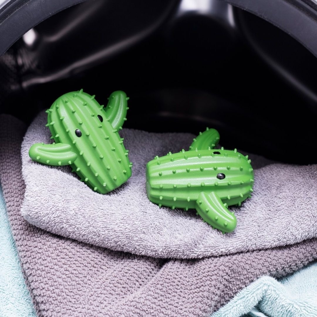 a pair of cute cactus-shaped dryer balls on a bed of fresh towels