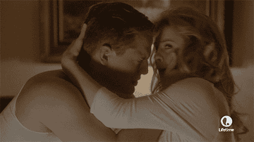 A blonde man and a blonde woman embrace and look towards the screen in disgust and fear.