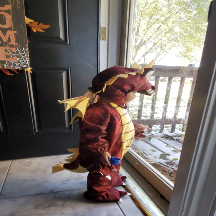 a reviewer photo of a child in the dragon costume looking out the door