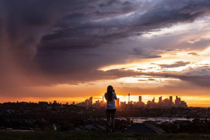 A person looks on as storm clouds roll over the city