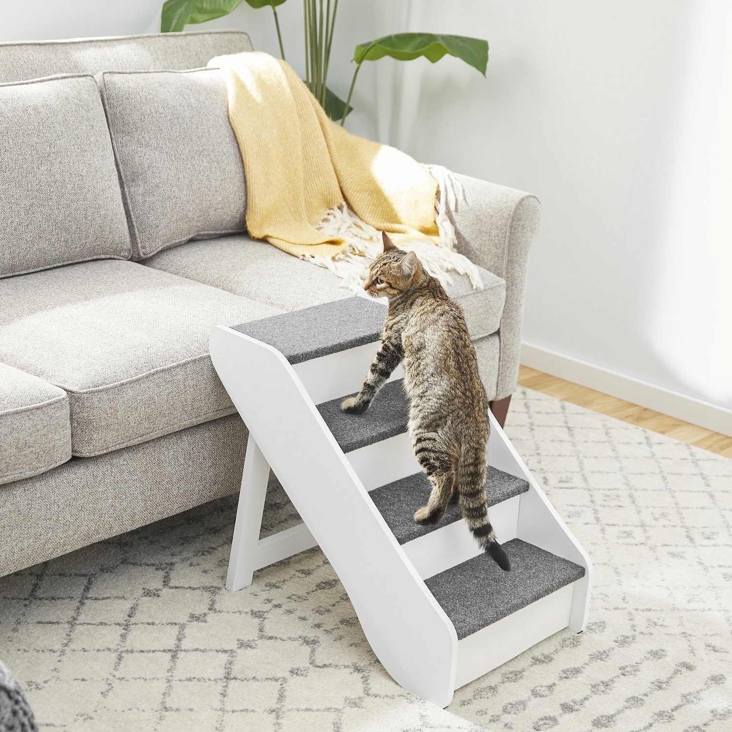 white and gray foldable pet stairs next to a couch with a cat on them