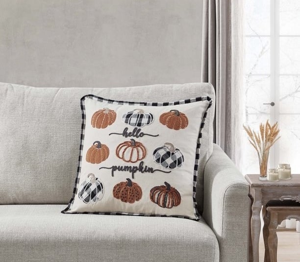 The pillow, which says &quot;hello pumpkin,&quot; on a couch.