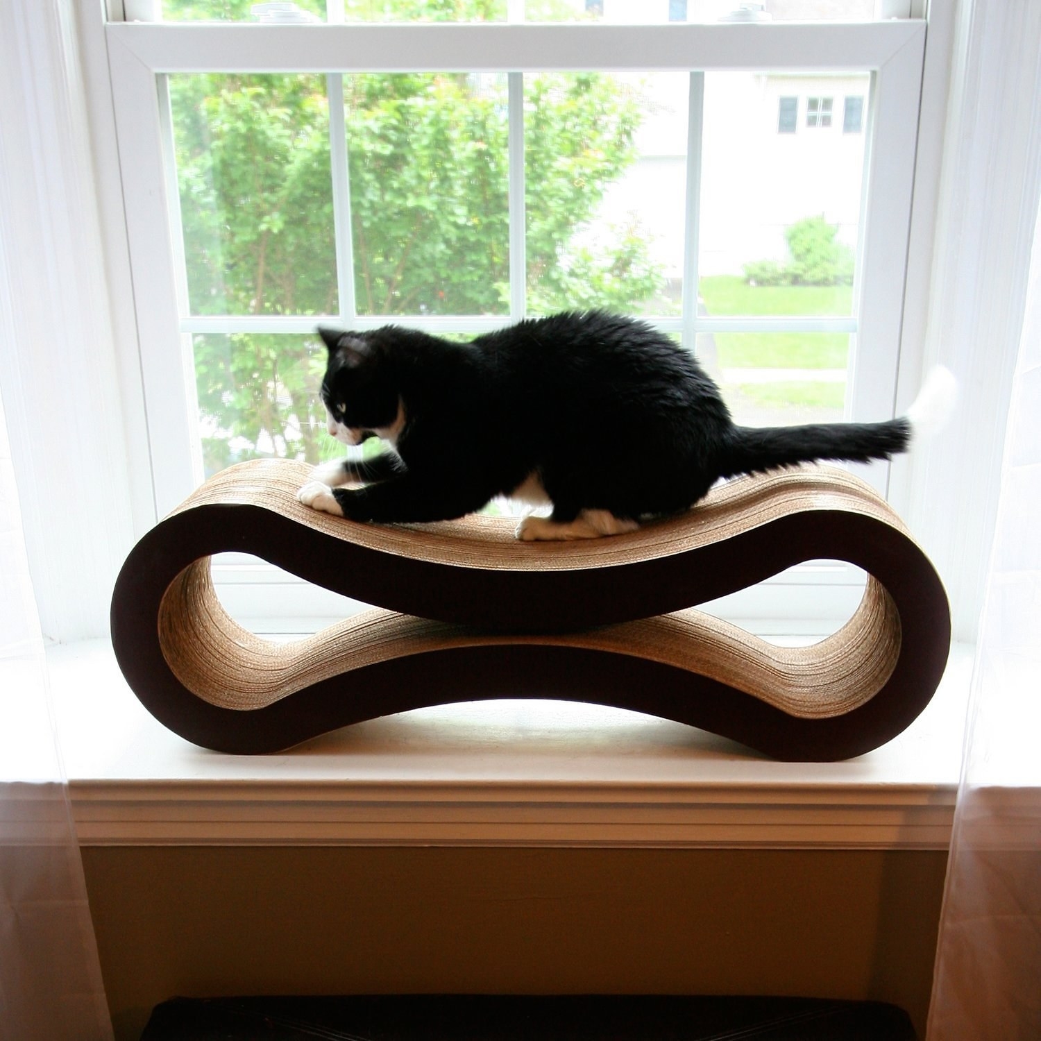 walnut brown colored, curved cat scratcher and lounge with a cat on top