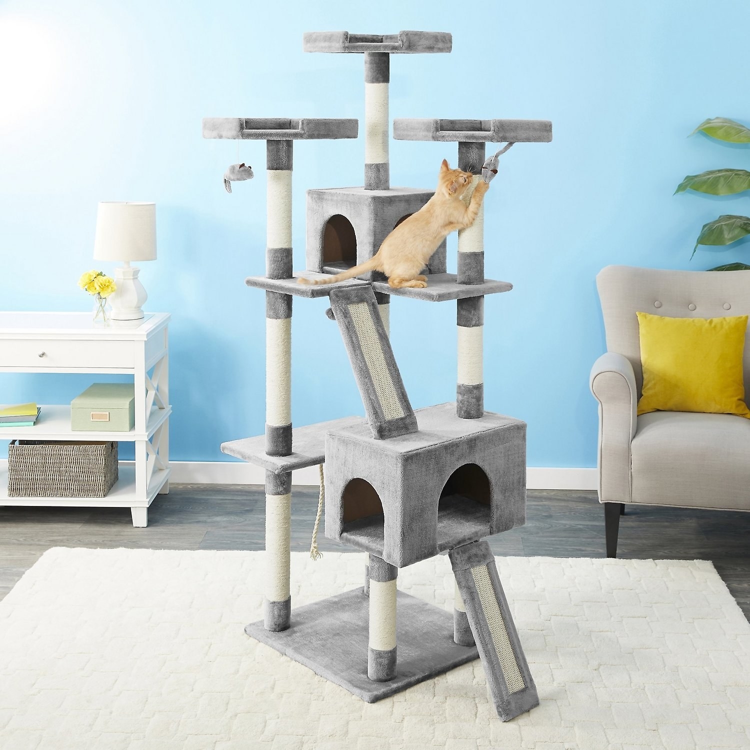 three level cat condo with perches, slides, toys and scratchers, and a kitten playing on it
