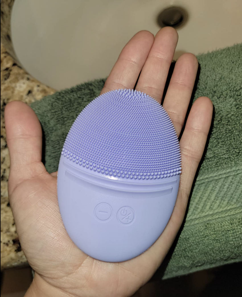 reviewer holding the purple cleaning brush