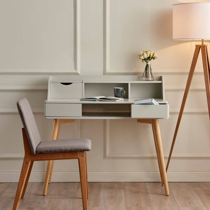 Desk with writing accessories and a chair and floor lamp next to it