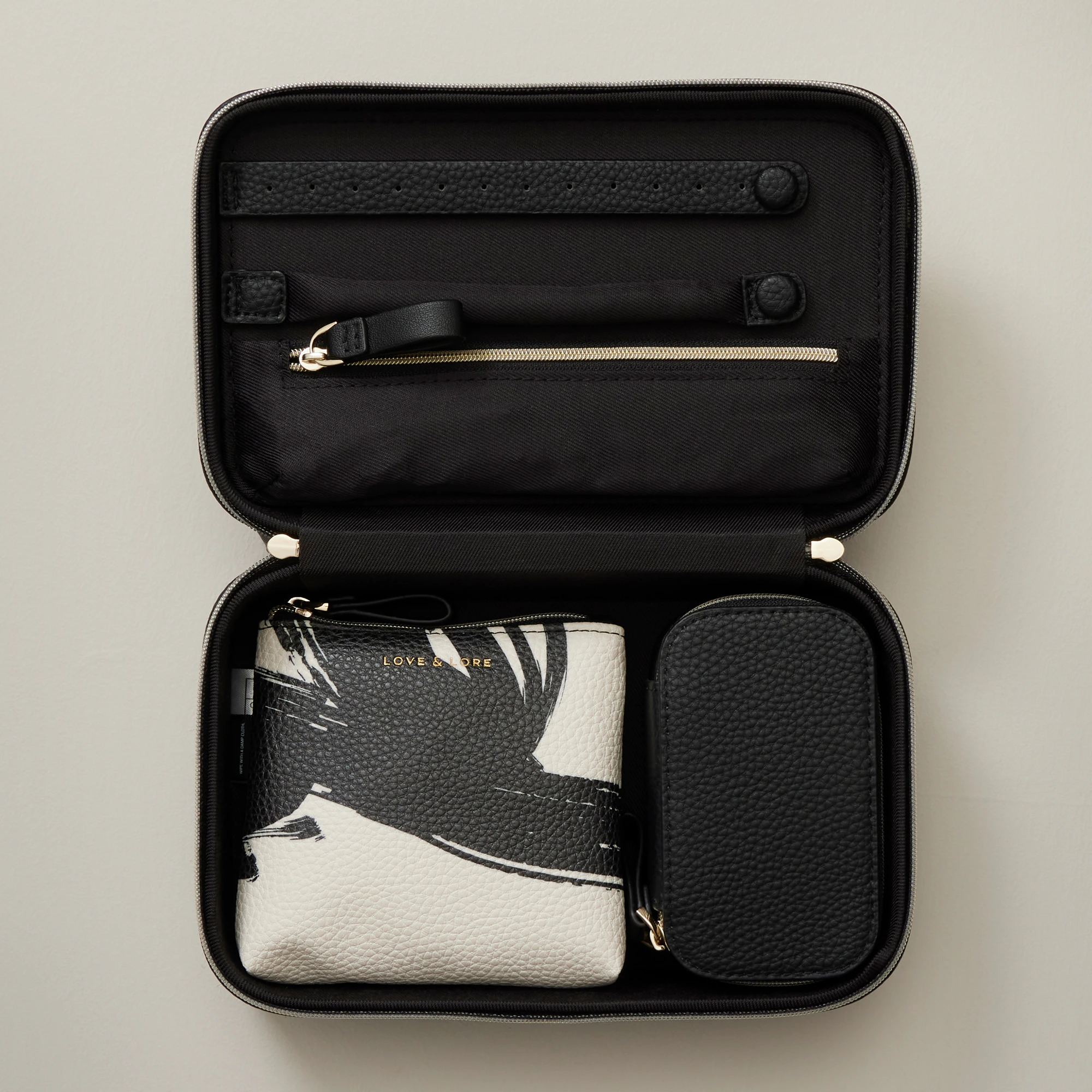An open faux leather jewellery case with smaller fabric bags inside