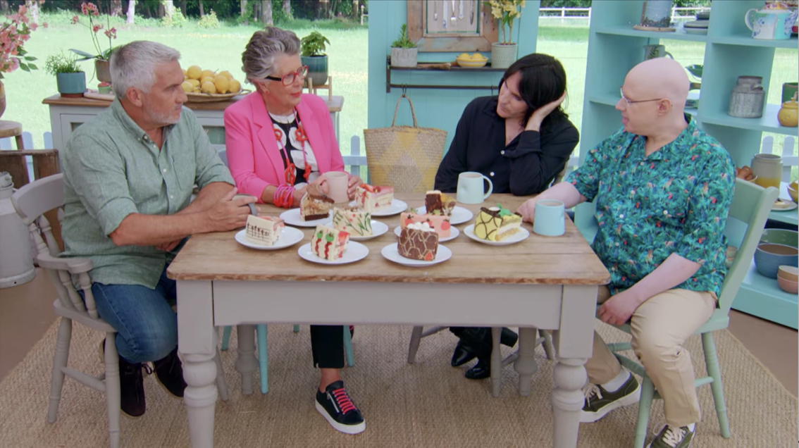 The judges and hosts sitting around the showstopper slices