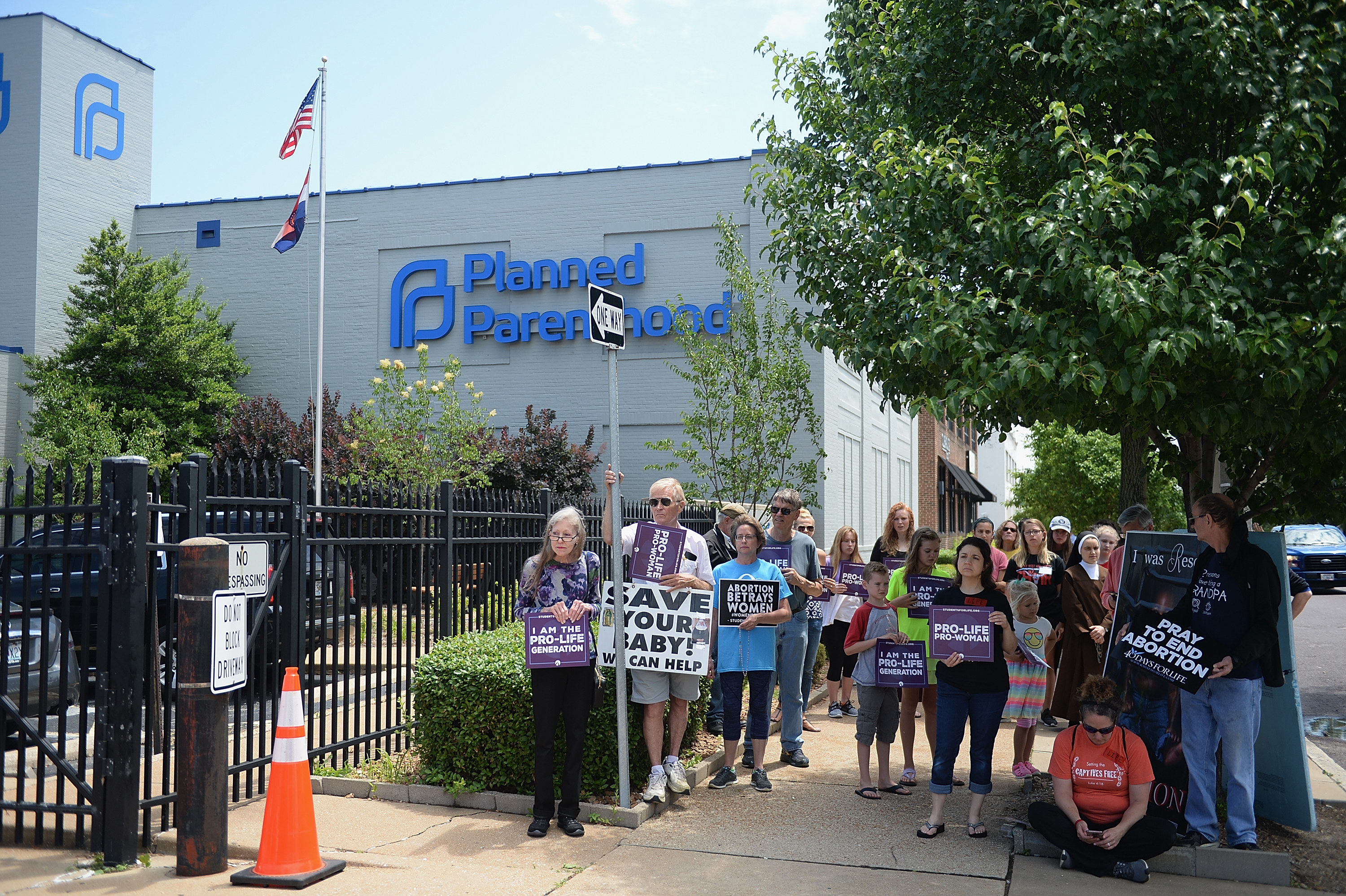 People stand holding signs, including &quot;Save your baby!&quot; and &quot;Pray to end abortion&quot;