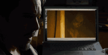 GIF of a person wearing a scary mask in a video on a laptop