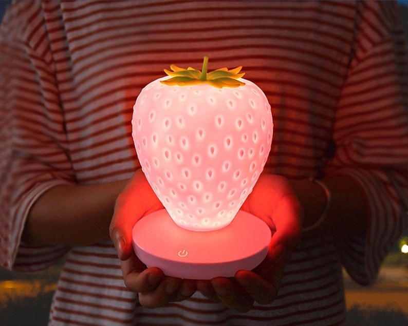 a model holding the pink strawberry nightlight