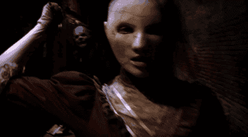 GIF of a person in a doll mask holding a knife