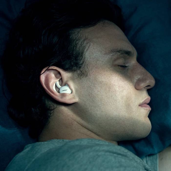 a person sleeping on their side while wearing the sleep pods in their ears