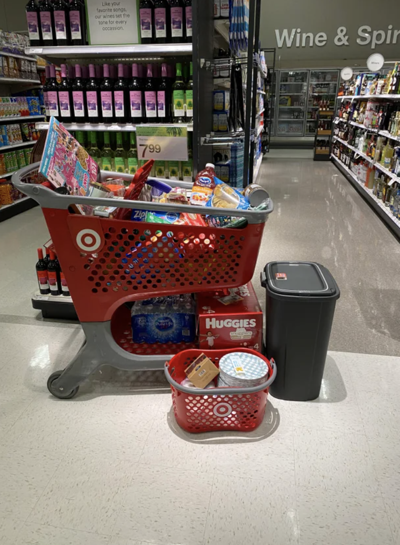 Target cart full of items, like juice, diapers, water bottles, paper plates, and a garbage can