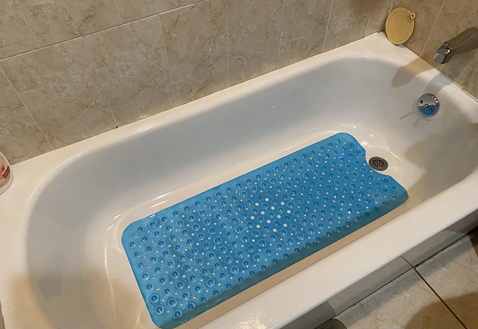 Reviewer&#x27;s photo of the blue bath mat with a pebble design in their bath tub