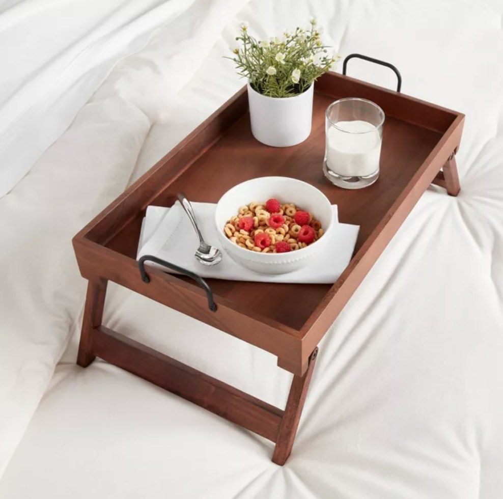 the wooden serving tray with breakfast on top in bed