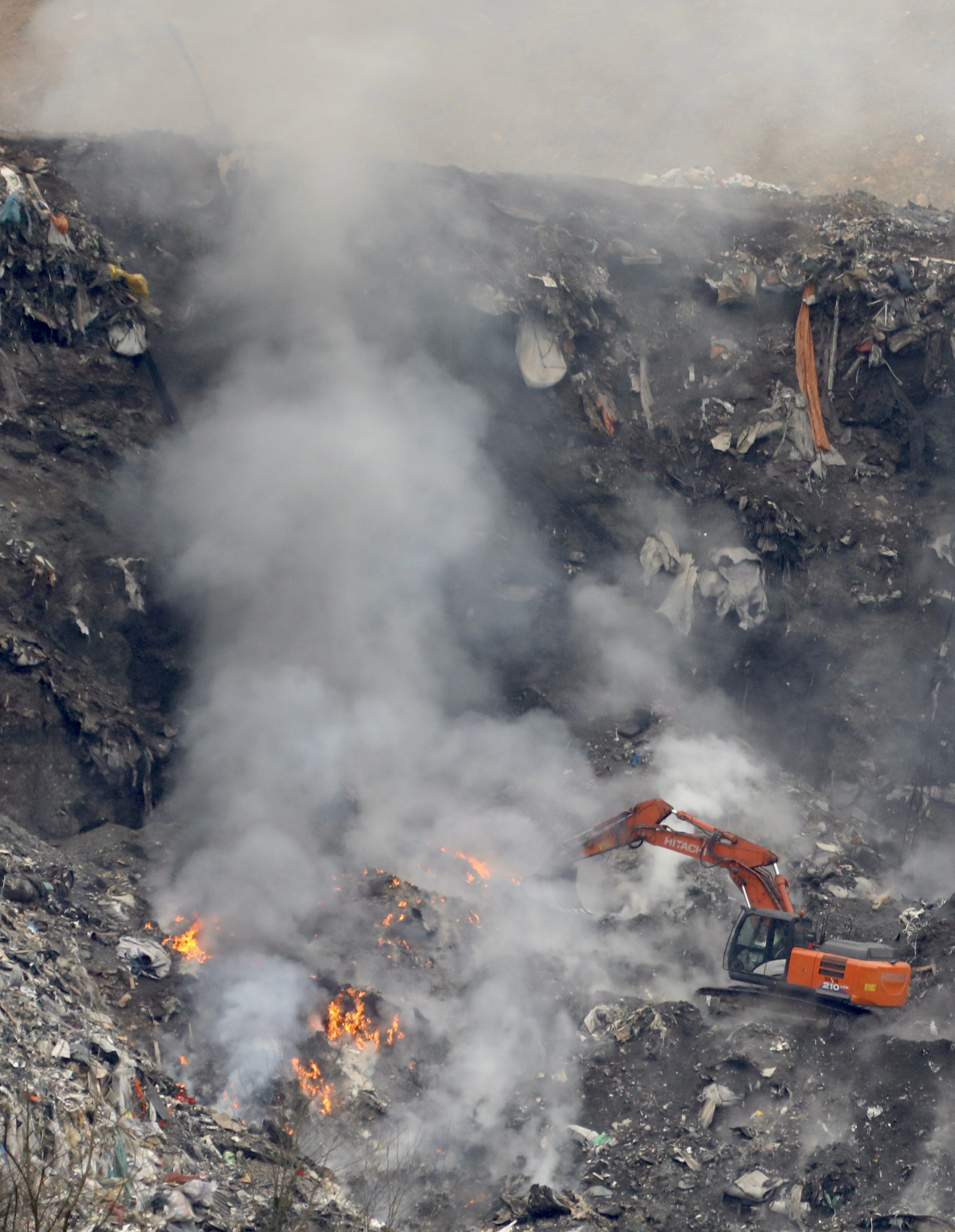 A bulldozer works to put out a fire at a landfill in Spain