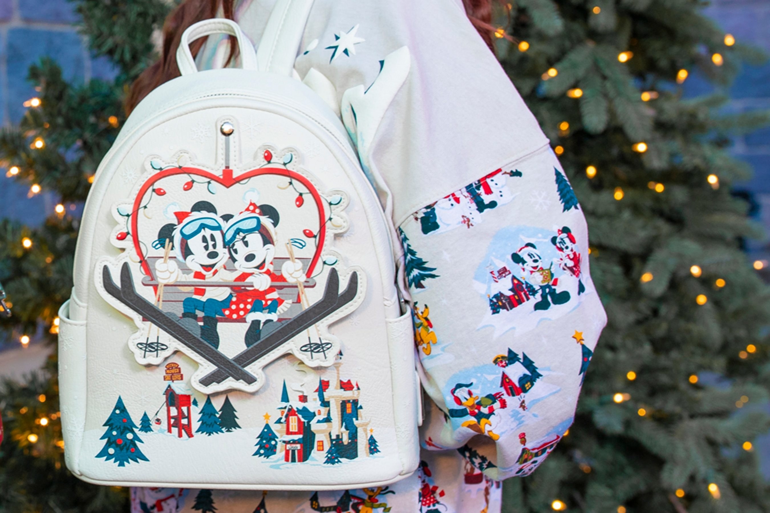 A white leather backpack with minnie and mickey on a ski lift shaped like a heart