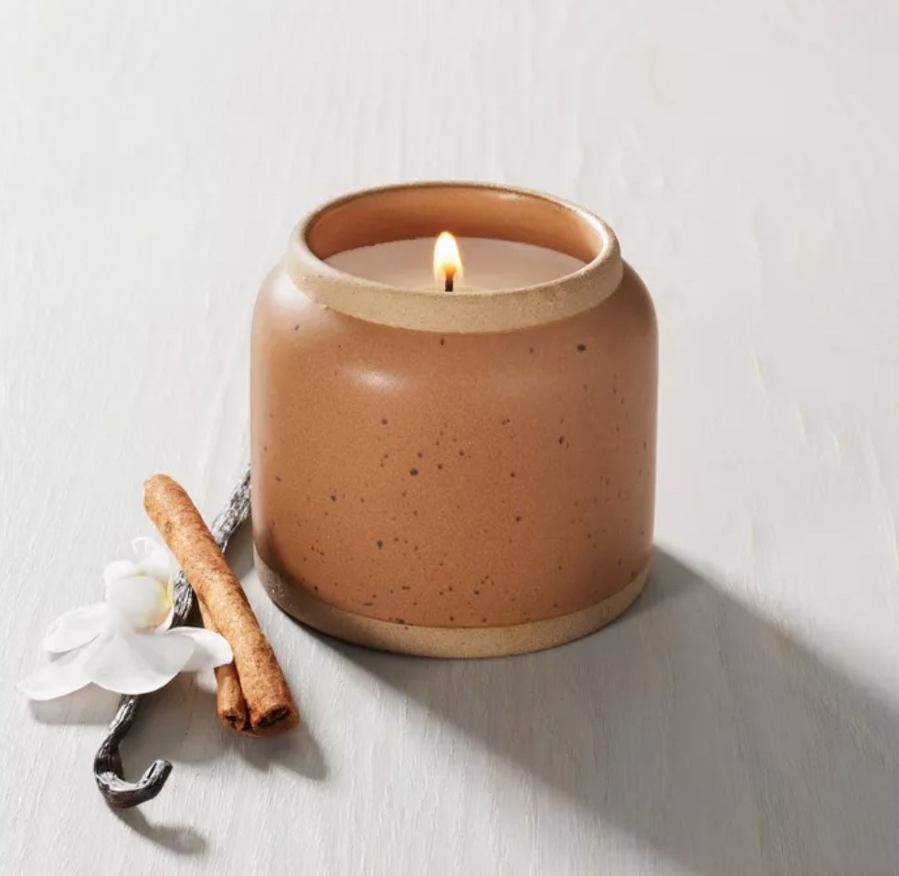 the candle in a speckled tan ceramic holder