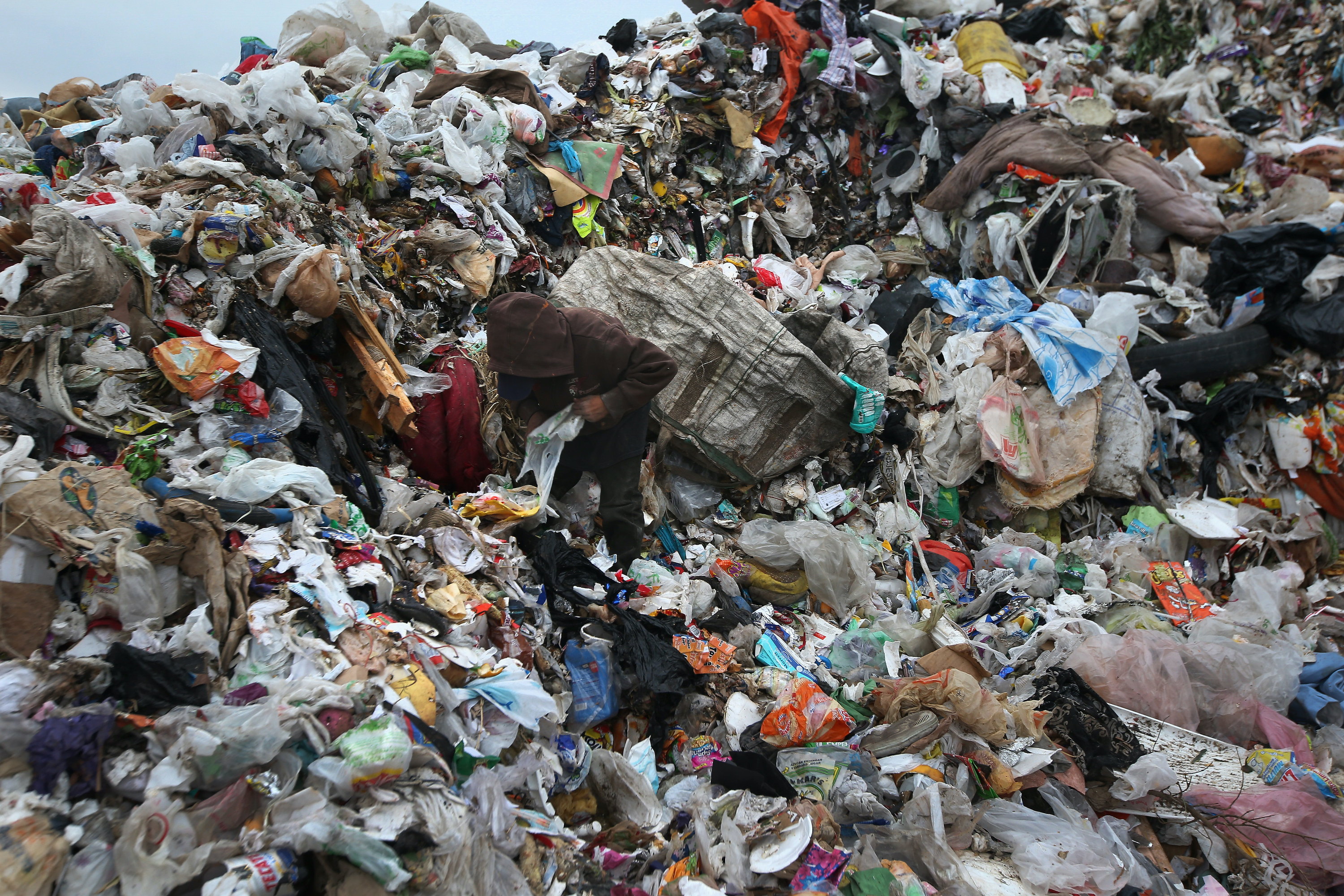 A person climbs a mountain of trash in Mexico looking for items to sell