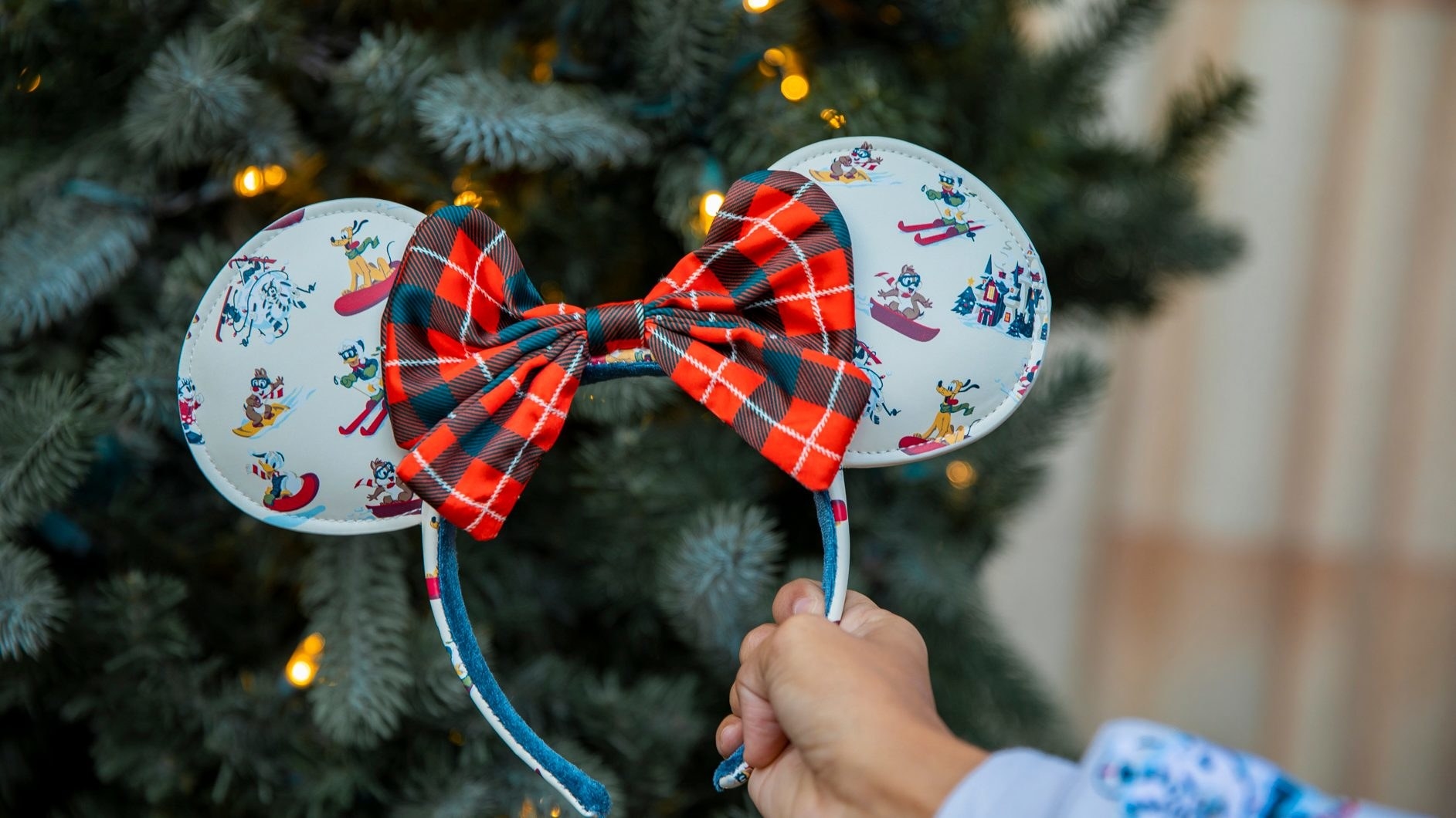 A pair of minnie ears with a plaid bow and winter scenes on the ears
