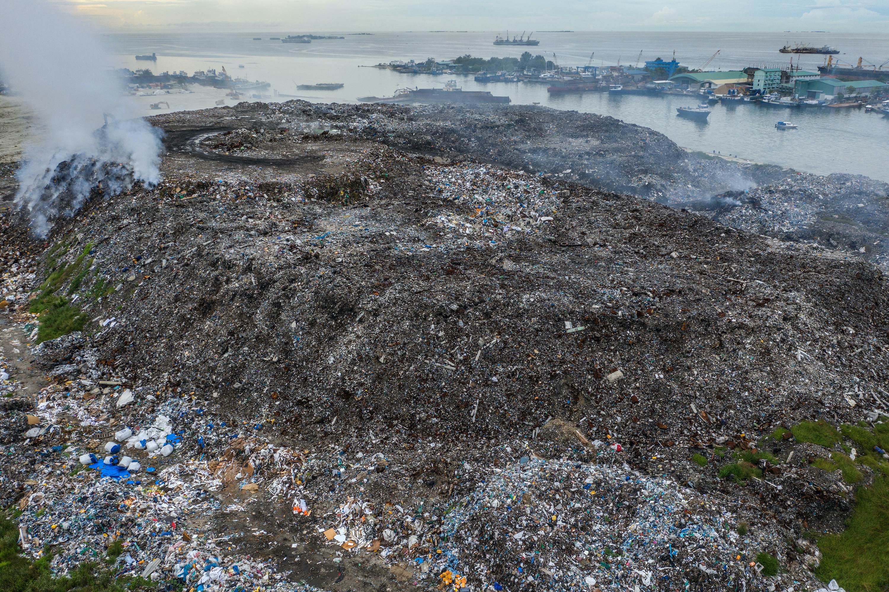 Aerial view of a landfill in the Maldives with smoke rising from the garbage