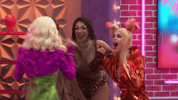 3 drag queens squealing excitedly to see each other.