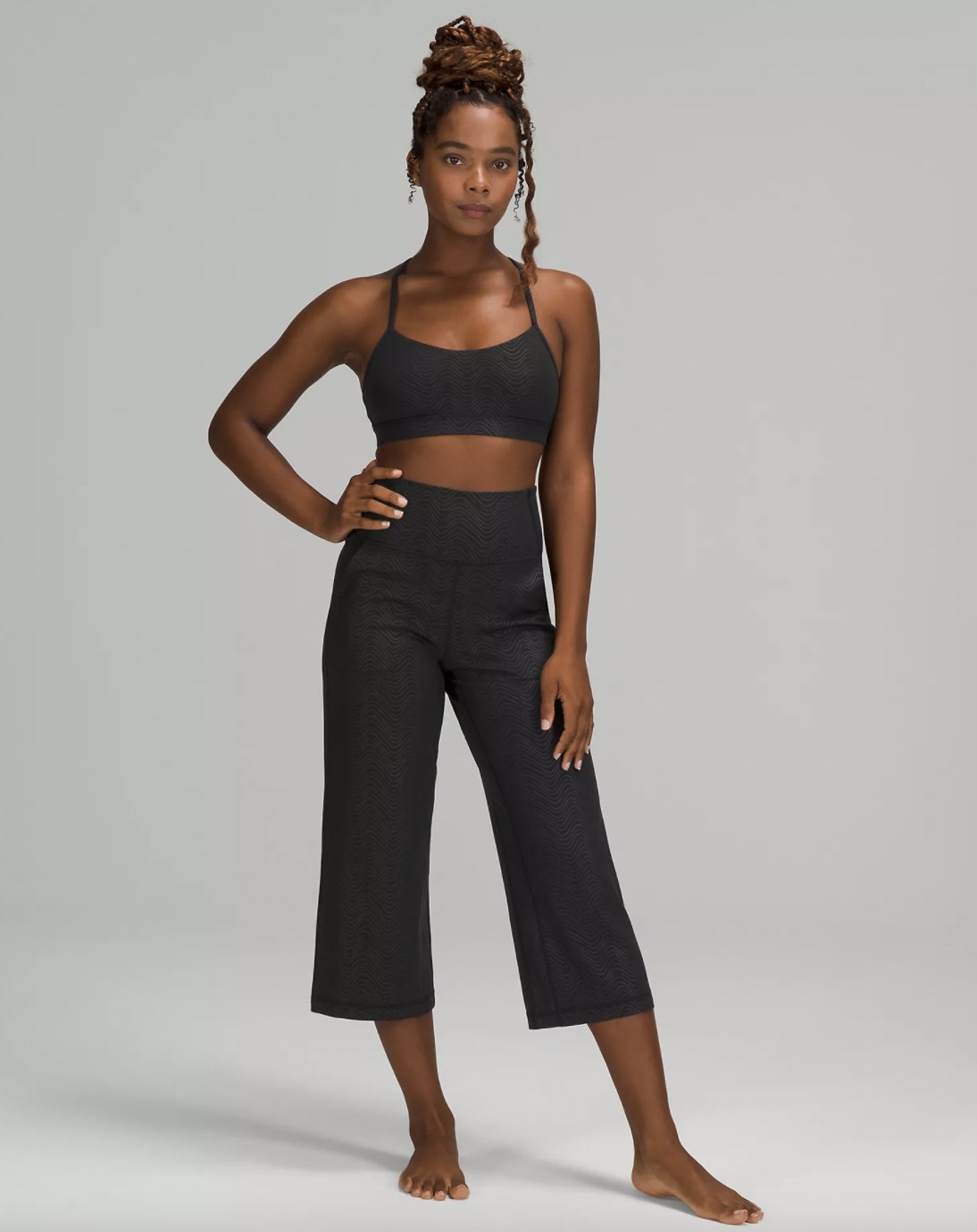A woman wearing a black sports bra and cropped pants