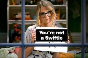 Taylor Swift is holding a sign that says "sorry, you're not a Swiftie"