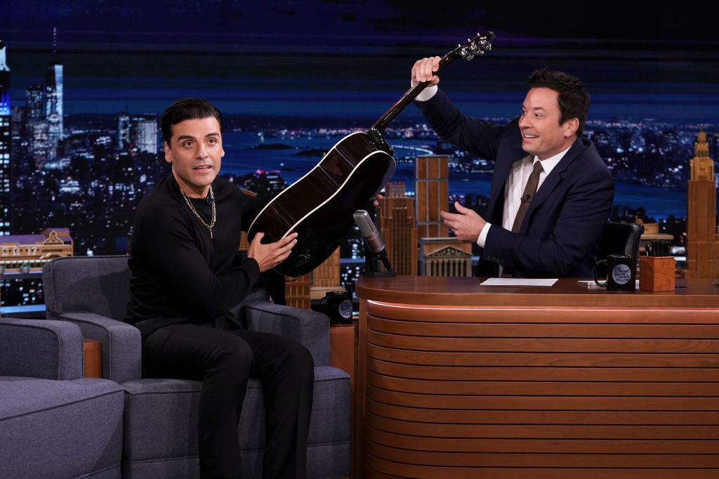 Oscar and Jimmy holding a guitar on the talk show set