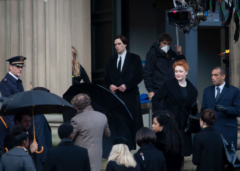 Robert as Bruce on set surrounded by people wearing dark colors