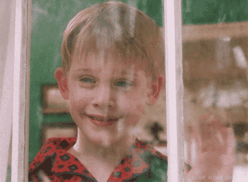 Macaulay Culkin waving from a snowy window in &quot;Home Alone.&quot;