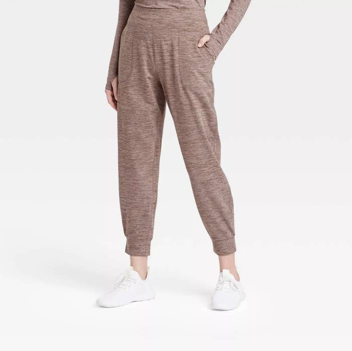 model wearing the joggers in light brown with matching long sleeve top and white shoes with one hand in the pocket