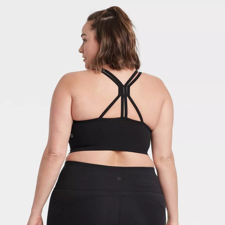 model showing off the back of the bra with center strap design and matching black bottoms