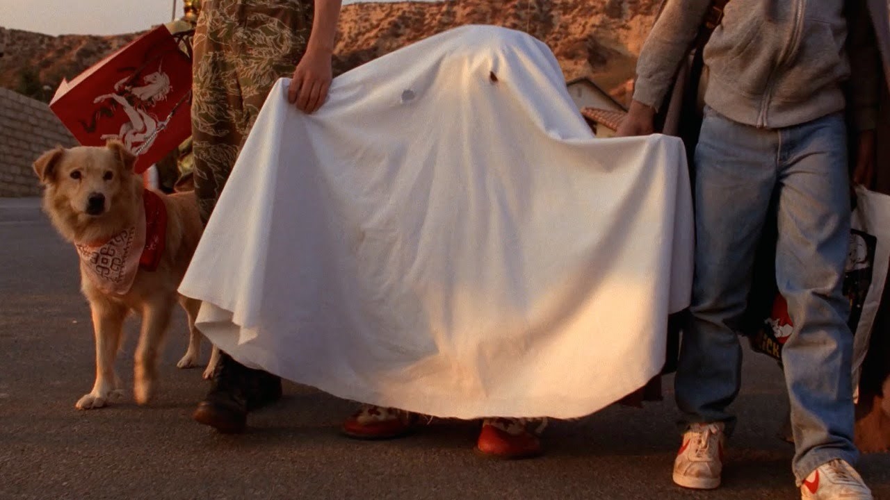 ET walks along the street as a ghost under a bedsheet