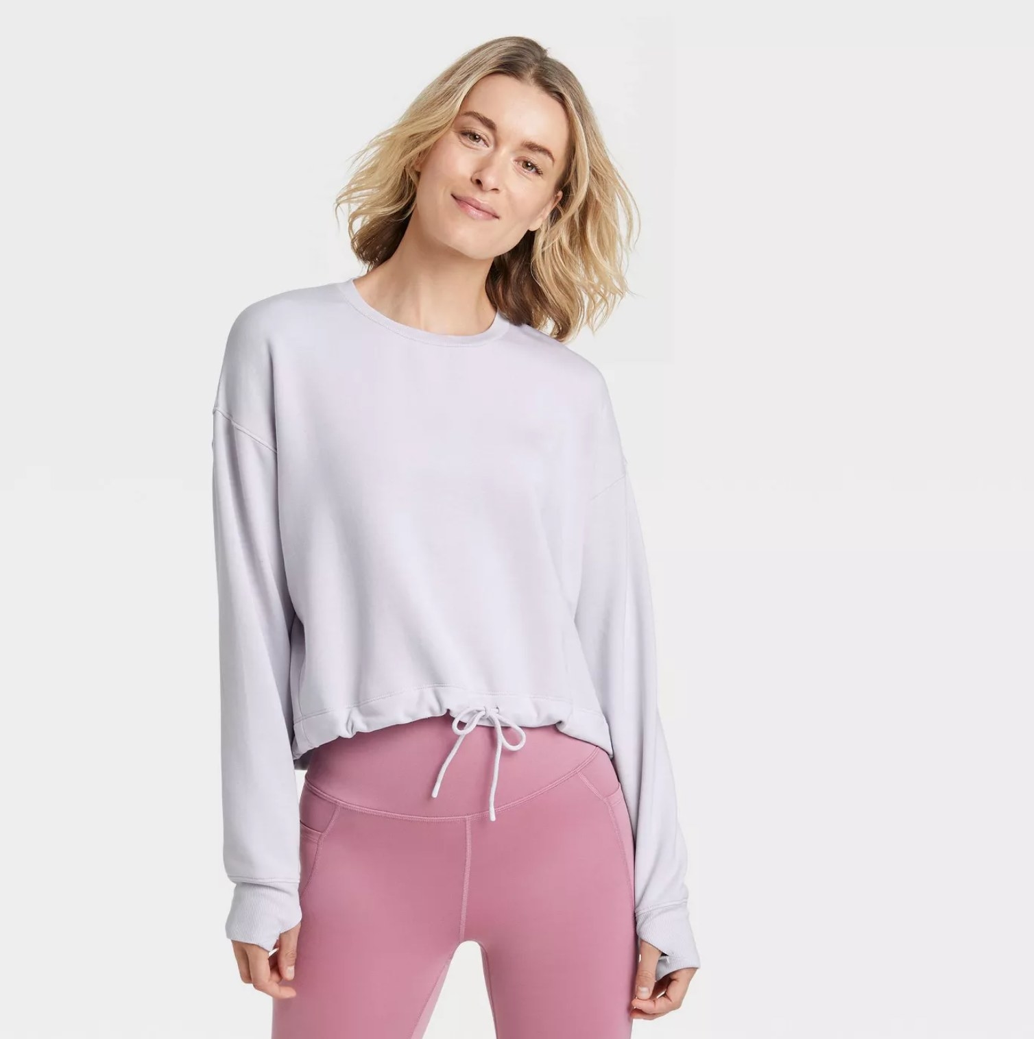 model wearing the pullover in white with tied waist and pink leggings