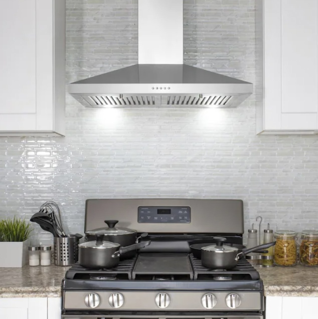 a silver wall-mounted hood above a stove