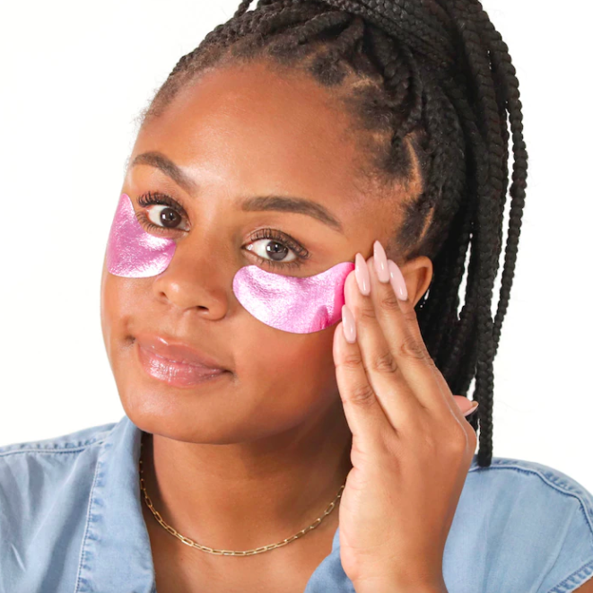 a person looking into the camera while applying the metallic eye patches