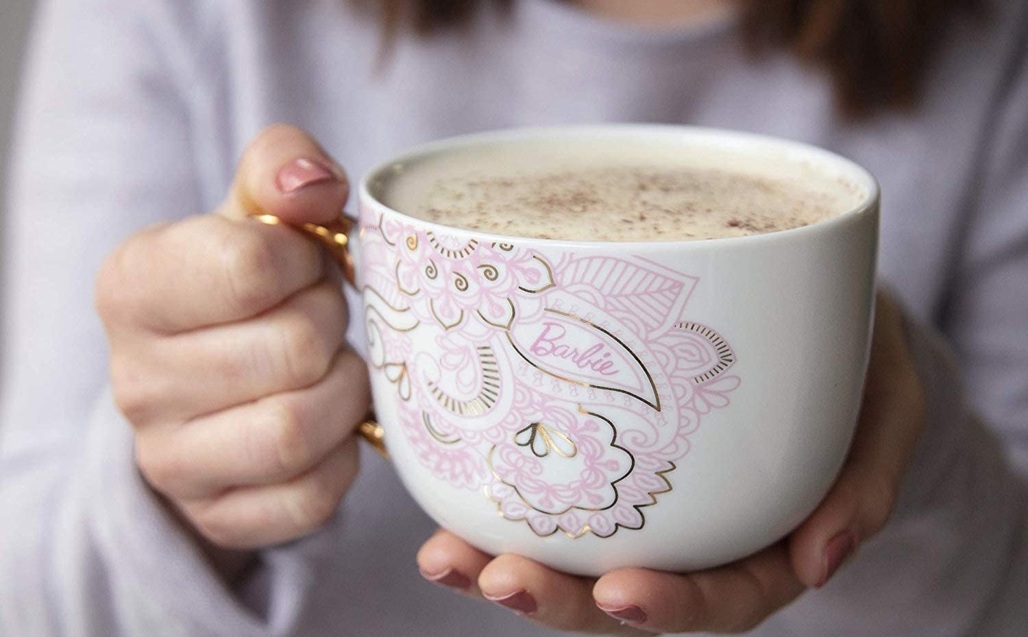 person holding a latte inside of a barbie mug