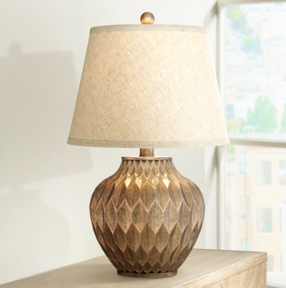 A bronze table lamp with a cream dome shade
